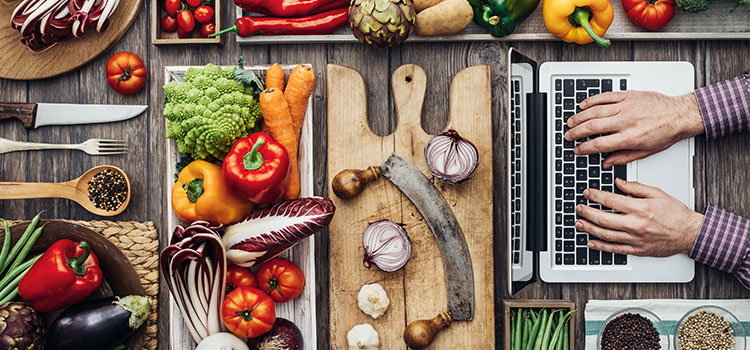 man using laptop for online studies near table of food