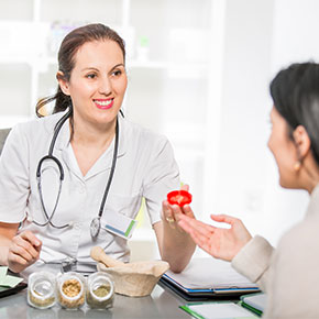 person with stethoscope handing red flower to patient