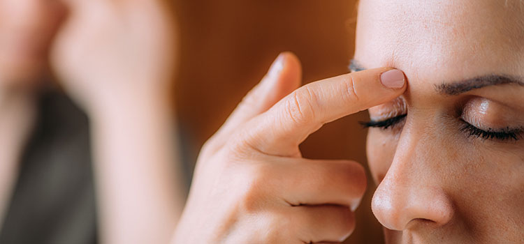 woman with closed eyes touh forehead with finger