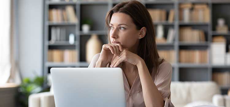 woman at desk with laptop pondering education options