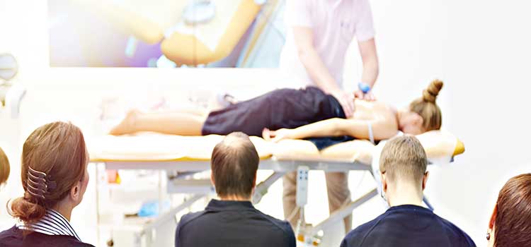 students watch massage teacher practice on client