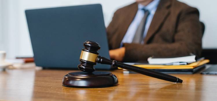 a judges hammer sits across a person working on their laptop