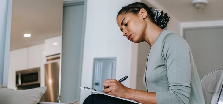 woman sitting in her living room filling our a form with a focused stare