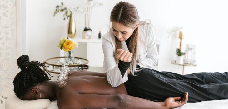 a holistic health practitioner applying elbow pressure and cupping therapy to patient