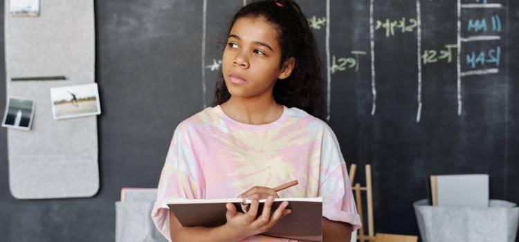 female student with notepad in hand staring pensively into distance