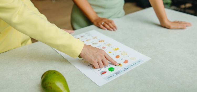 nutritionist points to a food table on a counter with an avocado next to it