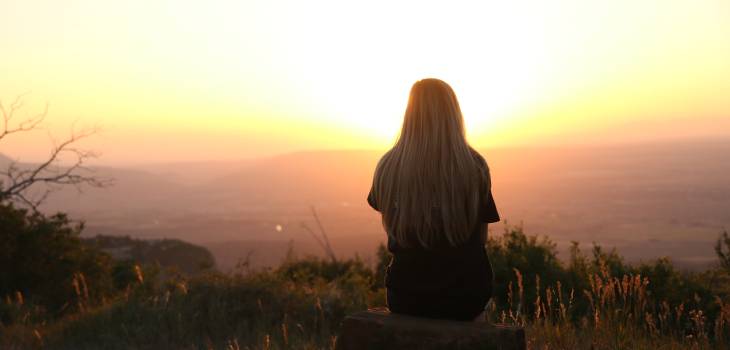 woman watching the beautiful sunset from atop a hill