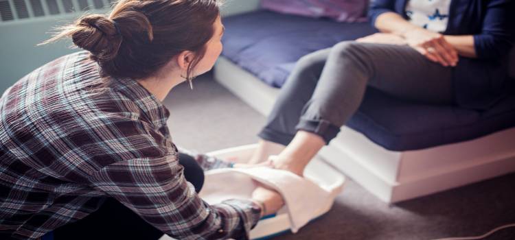 a reflexologist massaging their clients left foot during a session