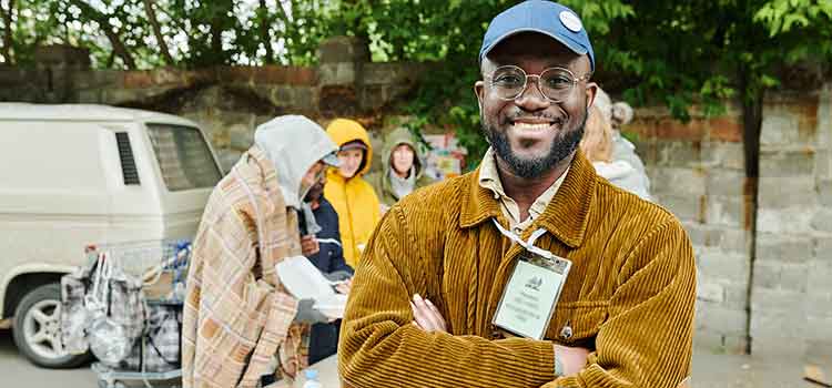 male social worker stands with community volunteers