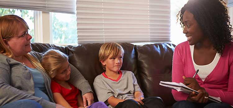 female social worker smiles as she takes notes during family session