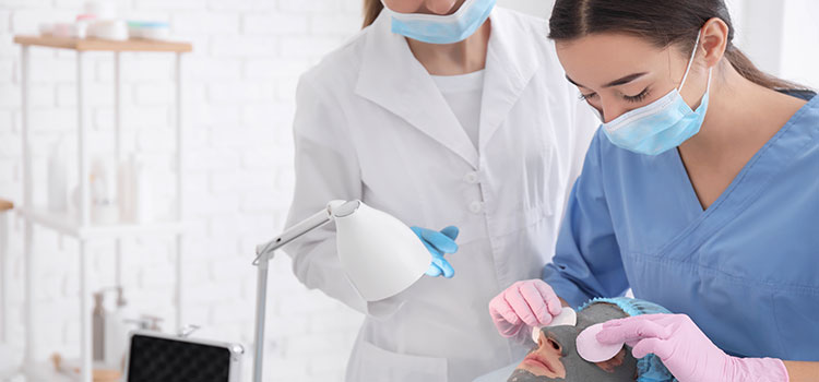 skin care student practices facial masque with teacher watching