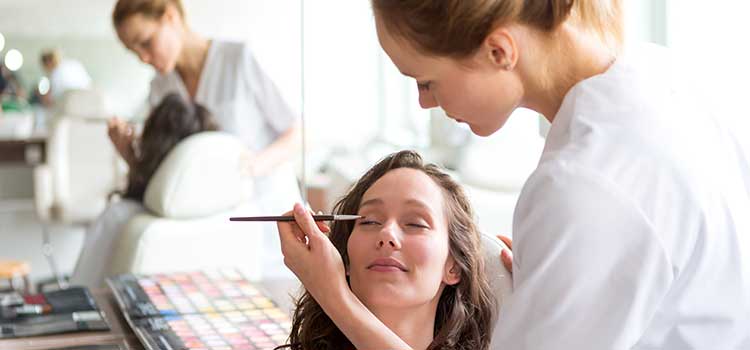 cosmetologist student works on fellow students face for practice