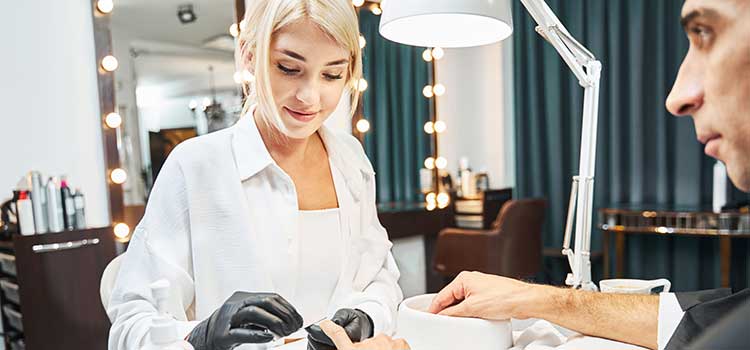 cosmetologist gives manicure to male client