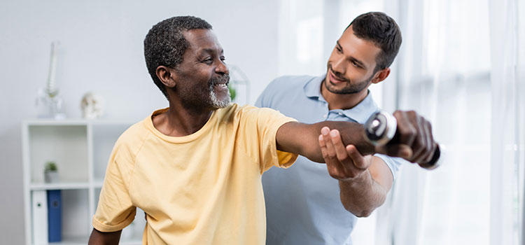 pt helps man straighten arm holding weight