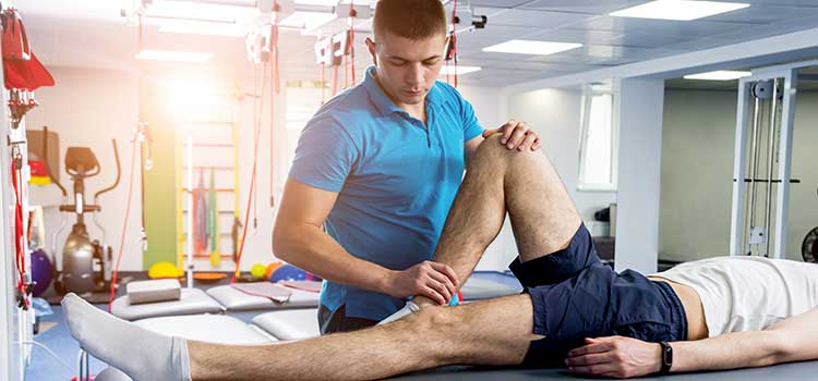 physical therapist helps patient with knee injury