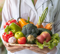nutritionist in white coat holds basket of assorted fruits and vegetables