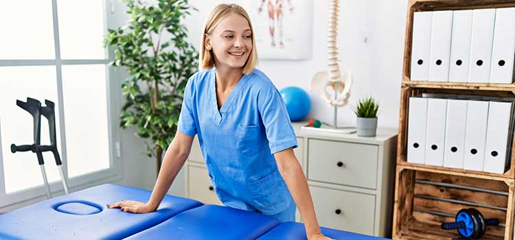 physical therapist leans on table and waits for client