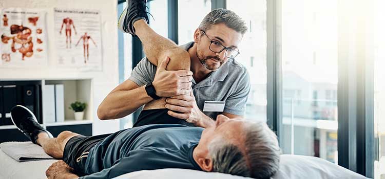 male physical therapist helps man rehab his leg