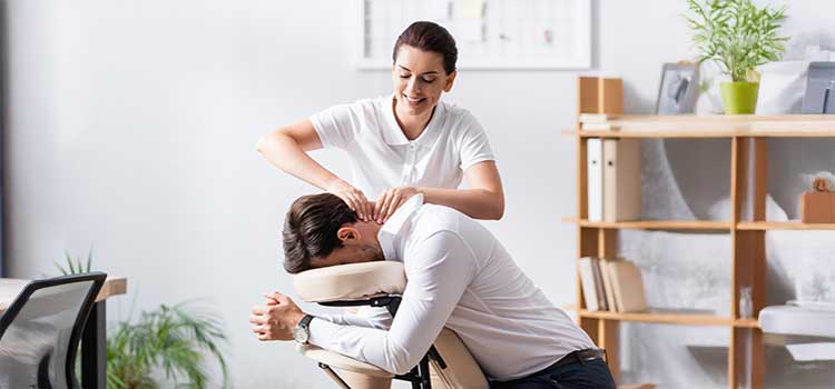 massage therapist gives male client a chair massage